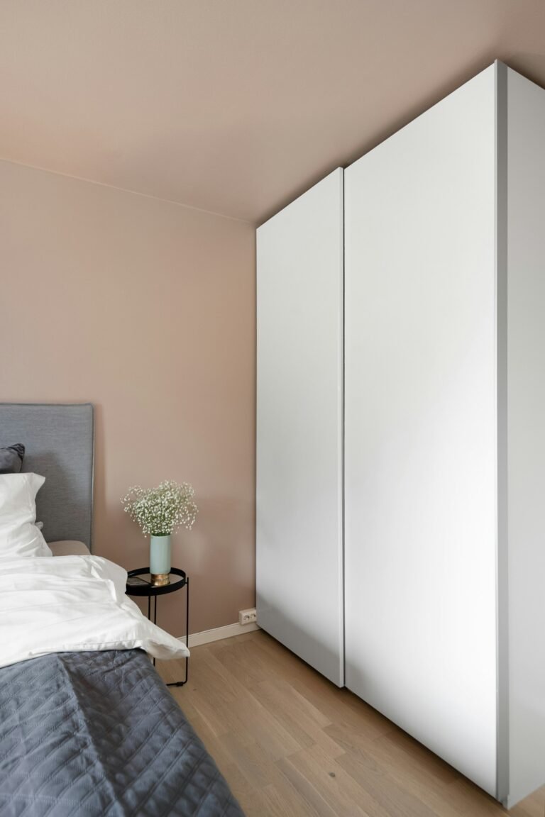White hinged wardrobe beside bed